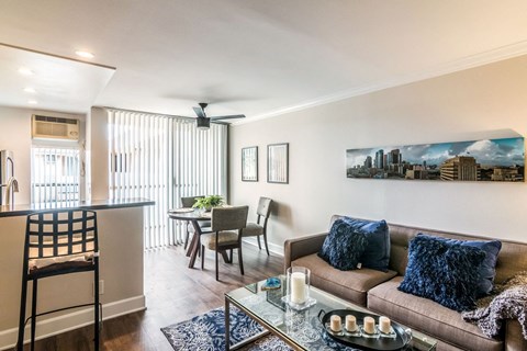 A living room with a brown couch and a painting of a city skyline on the wall.