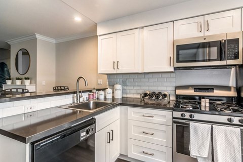 A kitchen with white cabinets and a black stove top.
