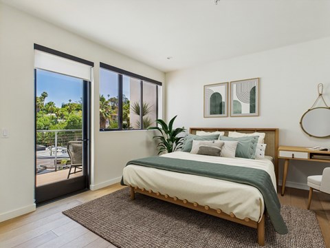 A bedroom with a large bed and a view of the outside through the sliding glass doors.