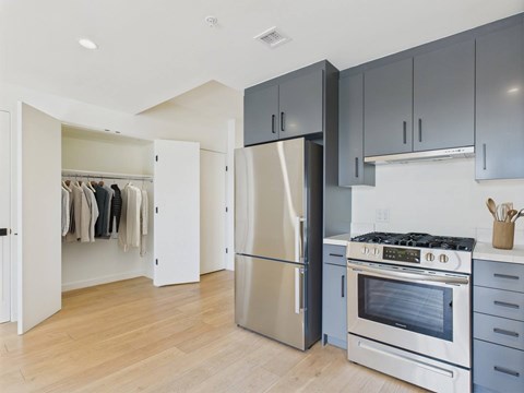 A kitchen with a stainless steel refrigerator and oven, and wooden flooring.