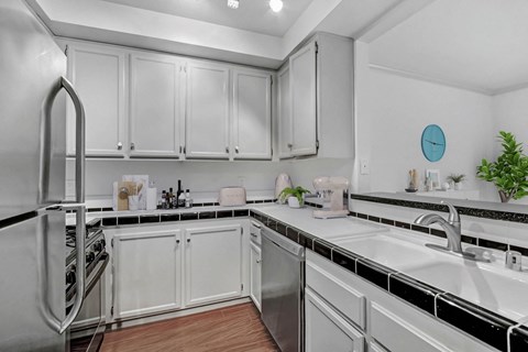 A kitchen with white cabinets and a black and white checkered backsplash.
