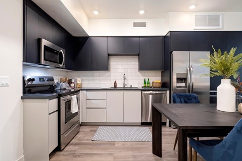 A modern kitchen with dark grey cabinets and stainless steel appliances.