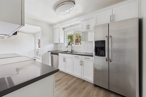 A modern kitchen with a stainless steel refrigerator and white cabinets.