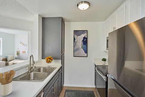 A kitchen with a stainless steel refrigerator and a painting of a woman on the wall.