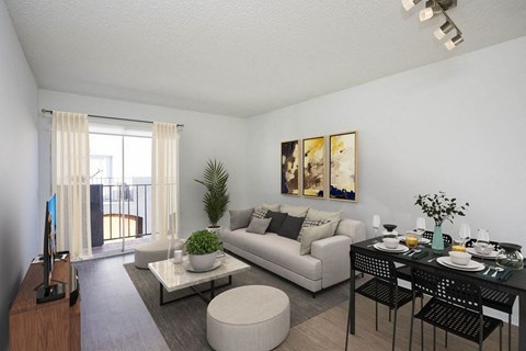 A living room with a white couch, a coffee table, and a dining table set for two.