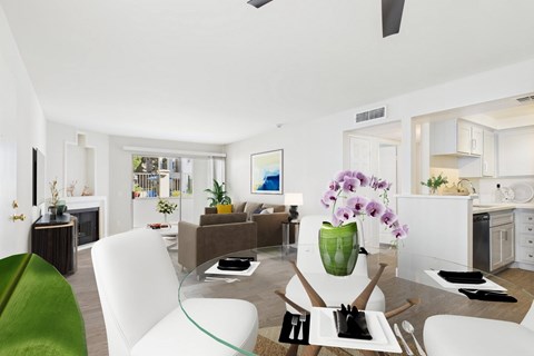 A modern living room with a glass table and white chairs.
