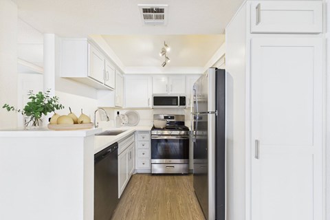 A modern kitchen with white cabinets and stainless steel appliances.