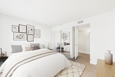 A white bedroom with a large bed and pictures on the wall.