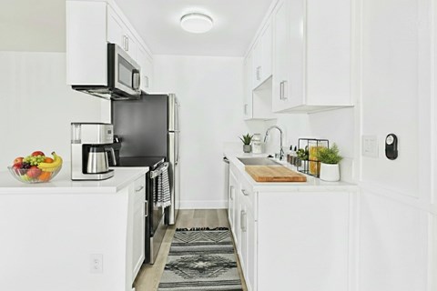 A modern kitchen with white cabinets and appliances.