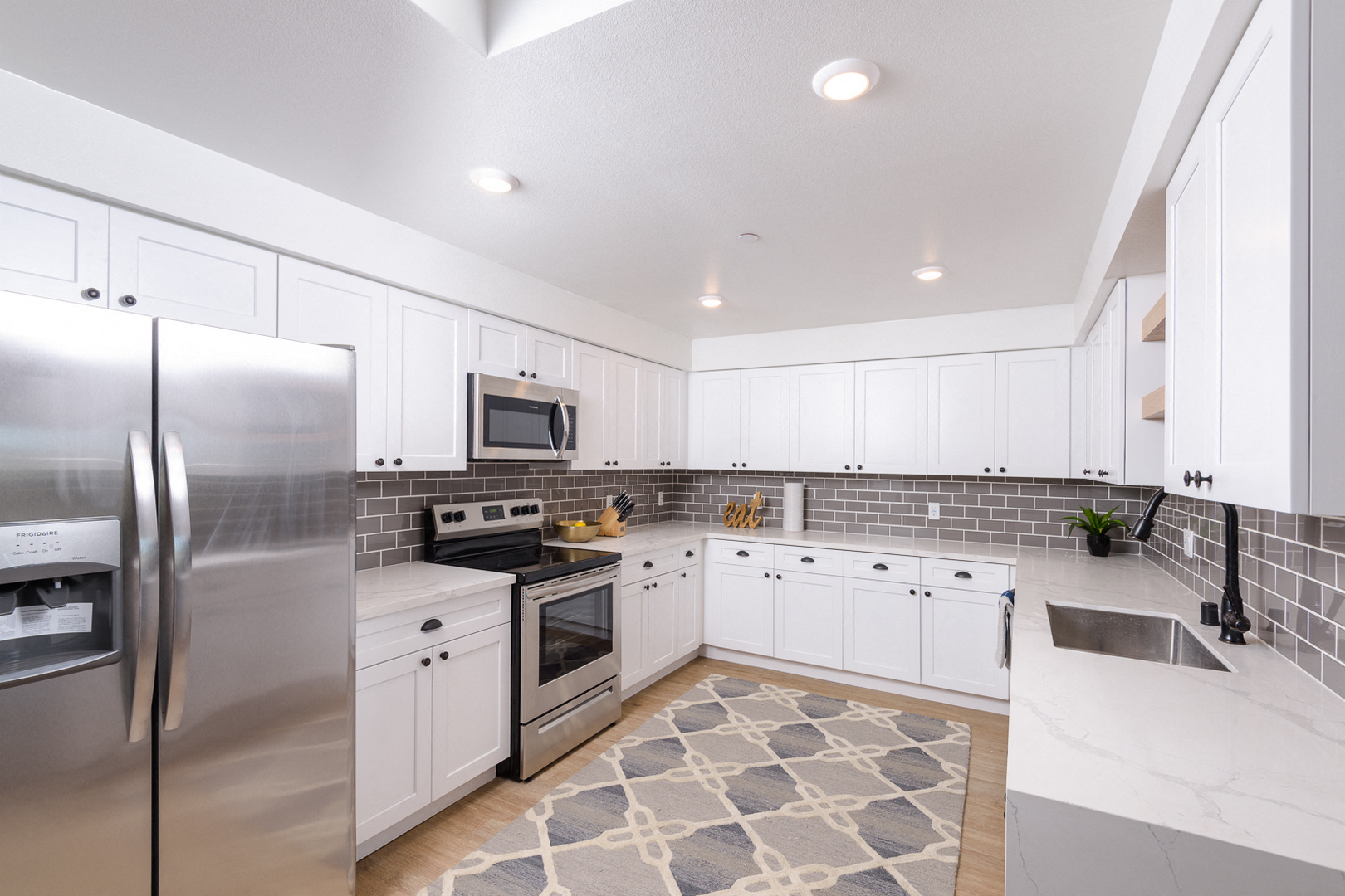 A modern kitchen with white cabinets and stainless steel appliances.