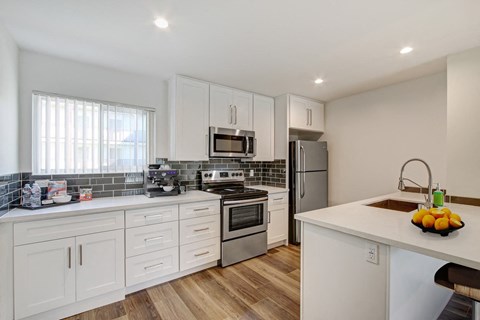 A kitchen with white cabinets and a wooden counter top.