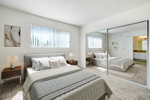 A bedroom with a large bed and a mirrored closet door.