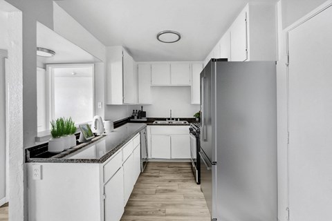 A modern kitchen with white cabinets and a refrigerator.