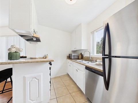A kitchen with a stainless steel refrigerator and white cabinets.