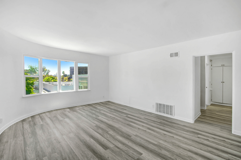an empty living room with white walls and wood floors