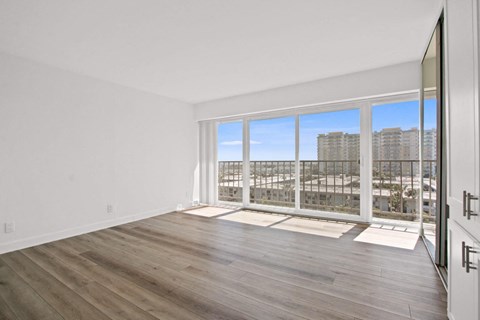 A spacious room with wooden floors and a large window overlooking a cityscape.