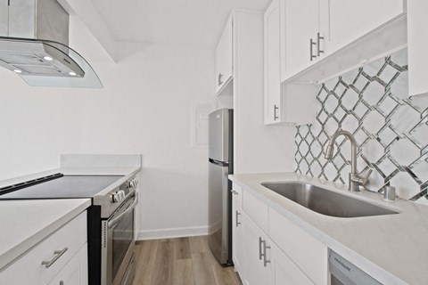 A kitchen with white cabinets and a black stove top oven.
