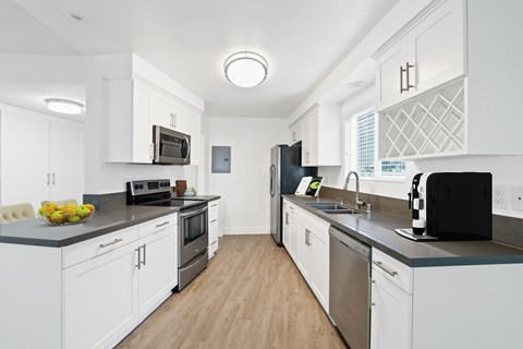 A modern kitchen with white cabinets and stainless steel appliances.