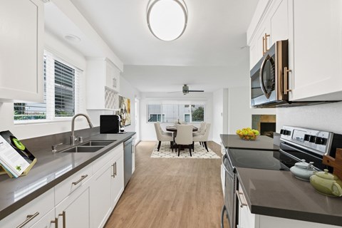 A modern kitchen with white cabinets and a wooden floor.