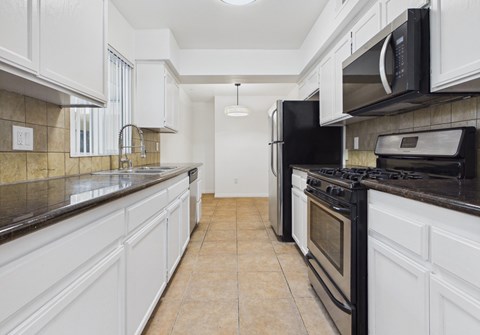 A kitchen with black appliances and white cabinets.