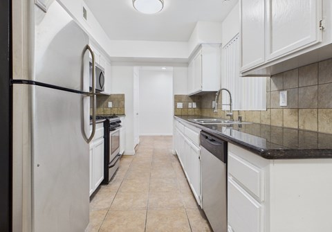 A kitchen with white cabinets and a black fridge.