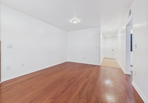 A long empty room with wooden floors and white walls.