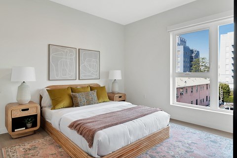 a bedroom with a large window and a large bed with a white comforter