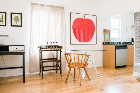 A kitchen with a table and chairs and a framed picture of an apple on the wall.
