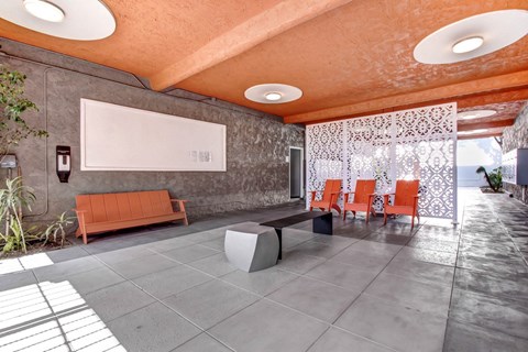 A modern living room with orange chairs and a grey bench.
