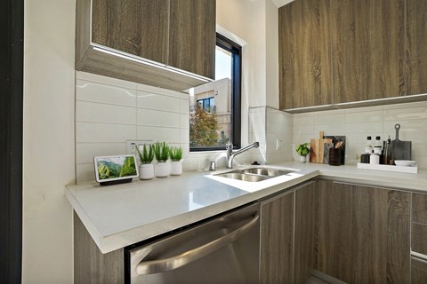 A modern kitchen with a stainless steel sink and wooden cabinets.