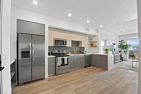 a modern kitchen with stainless steel appliances and a wooden floor