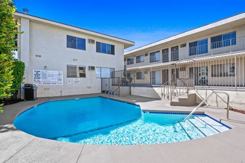 A swimming pool in front of a building with a sign on the wall.