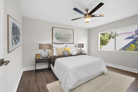 A bedroom with a white bed and a ceiling fan.