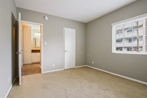 A room with a carpeted floor and a window with blinds.