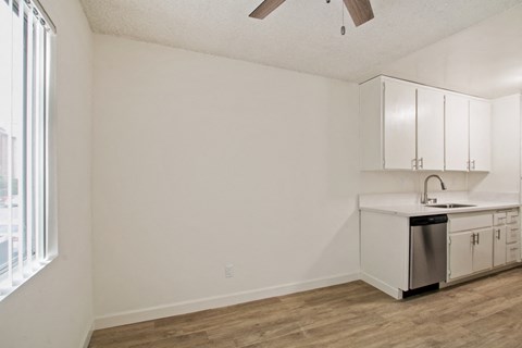 A kitchen with white cabinets and a wooden floor.