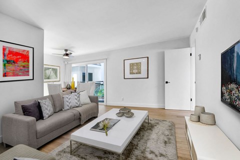 A living room with a grey couch, a white coffee table, and a painting on the wall.