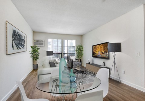 A living room with a glass table and white chairs.