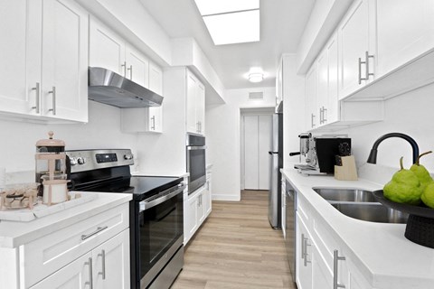 A modern kitchen with white cabinets and stainless steel appliances.