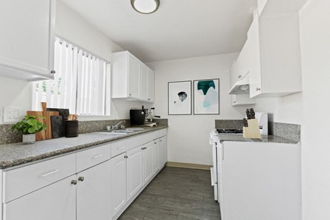 A kitchen with white cabinets and a grey countertop.