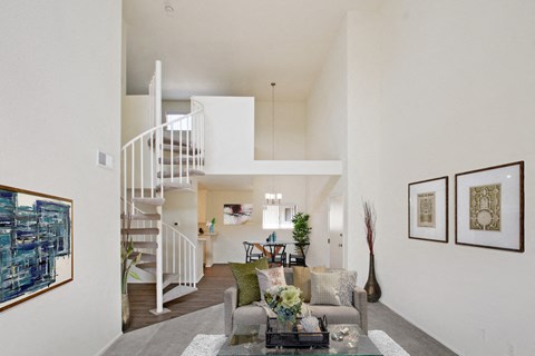 A living room with a staircase and a painting on the wall.