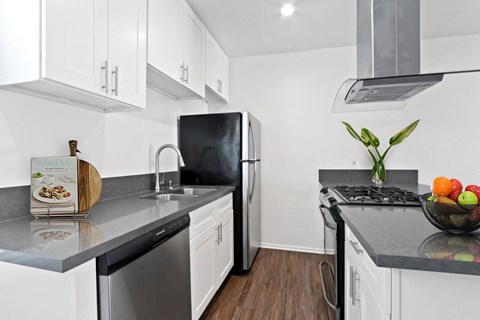 A kitchen with white cabinets and black countertops.