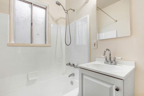 A white bathroom with a sink, mirror, and shower.