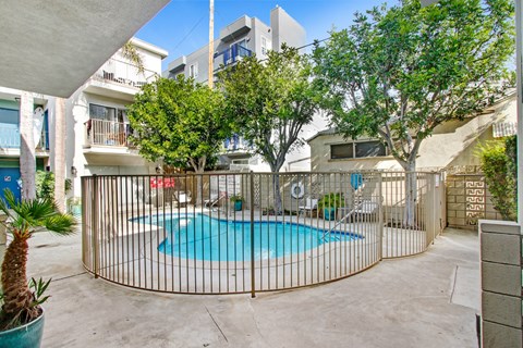 A pool surrounded by a fence and trees.