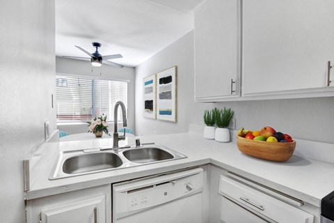 A kitchen with white cabinets and a bowl of fruit on the counter.