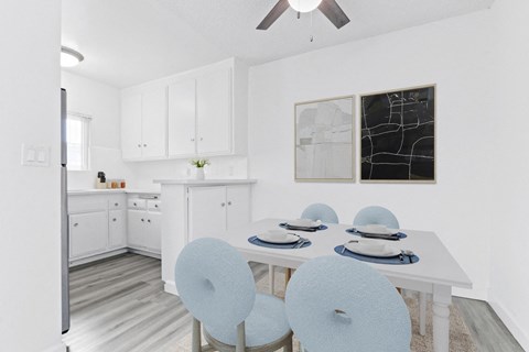 a white kitchen with a white table and blue chairs