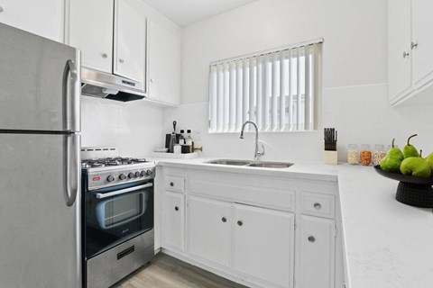 A modern kitchen with white cabinets and a stainless steel refrigerator.