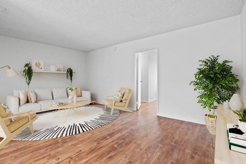 A living room with a white couch and a wooden floor.