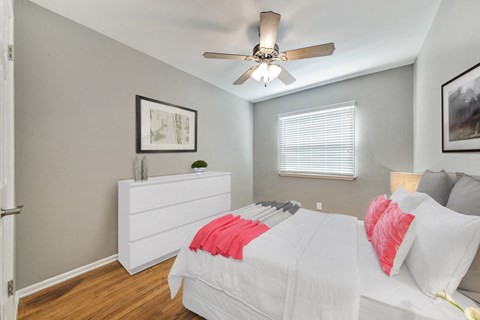 A bedroom with a white bed and a ceiling fan.