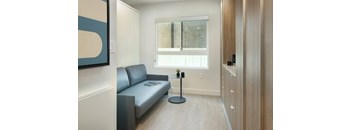 A grey sofa with a black table in front of a window.