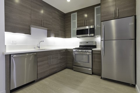 a kitchen with stainless steel appliances and wooden cabinets at Seventh West Apartments, Santa Monica 